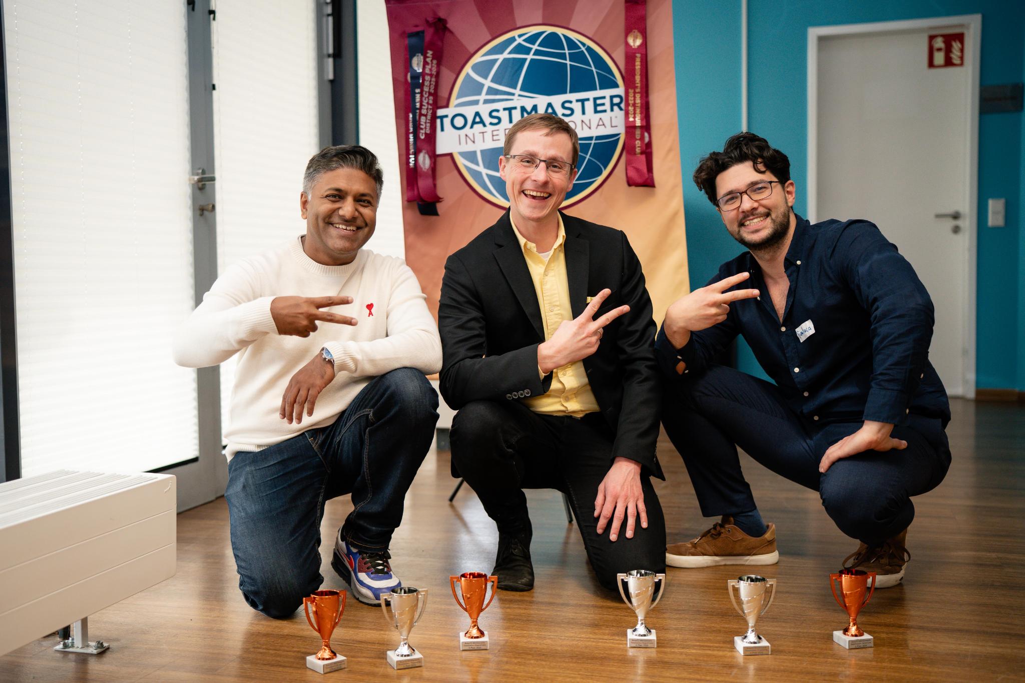 Gewinner der Area Competition 2026 mit Pokalen vor Toastmasters-Banner